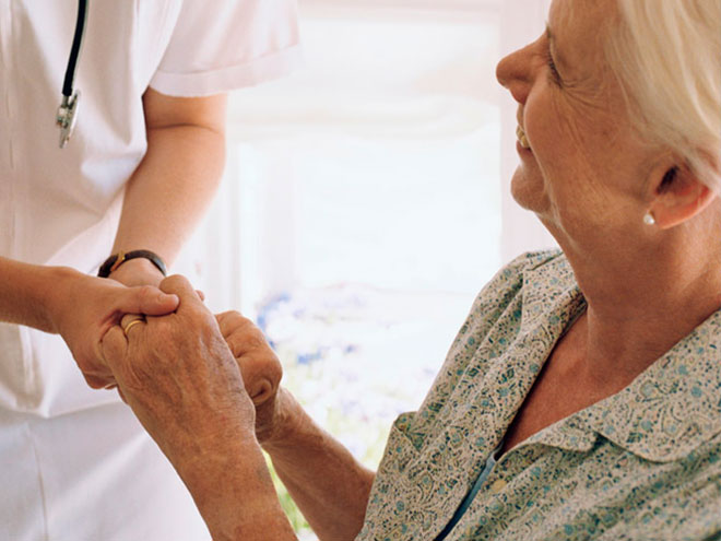 enfermera cogiendo manos de mujer mayor